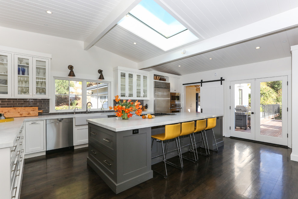 Photo of a contemporary l-shaped kitchen in San Francisco with a single-bowl sink, glass-front cabinets, white cabinets, granite worktops, multi-coloured splashback, stone tiled splashback, stainless steel appliances, dark hardwood flooring and an island.