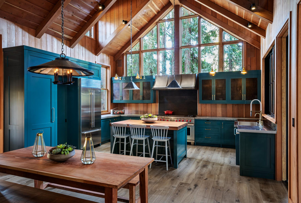 Foto di una grande cucina stile rurale con lavello integrato, ante in stile shaker, ante blu, top in granito, elettrodomestici in acciaio inossidabile, pavimento in legno massello medio, pavimento grigio e top grigio