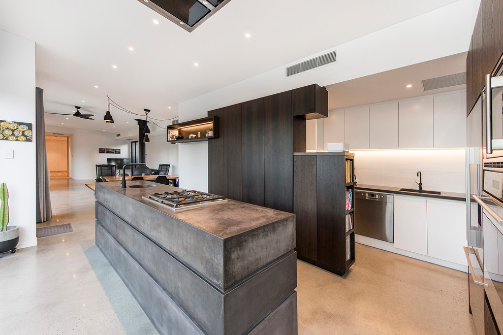 Contemporary u-shaped open plan kitchen in Perth with dark wood cabinets, concrete worktops, white splashback, porcelain splashback, concrete flooring, an island, grey floors, a submerged sink, flat-panel cabinets and stainless steel appliances.