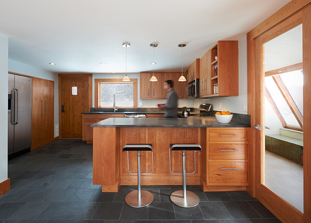 Design ideas for a medium sized contemporary u-shaped kitchen/diner in Burlington with a submerged sink, flat-panel cabinets, medium wood cabinets, soapstone worktops, black splashback, stainless steel appliances, slate flooring and a breakfast bar.