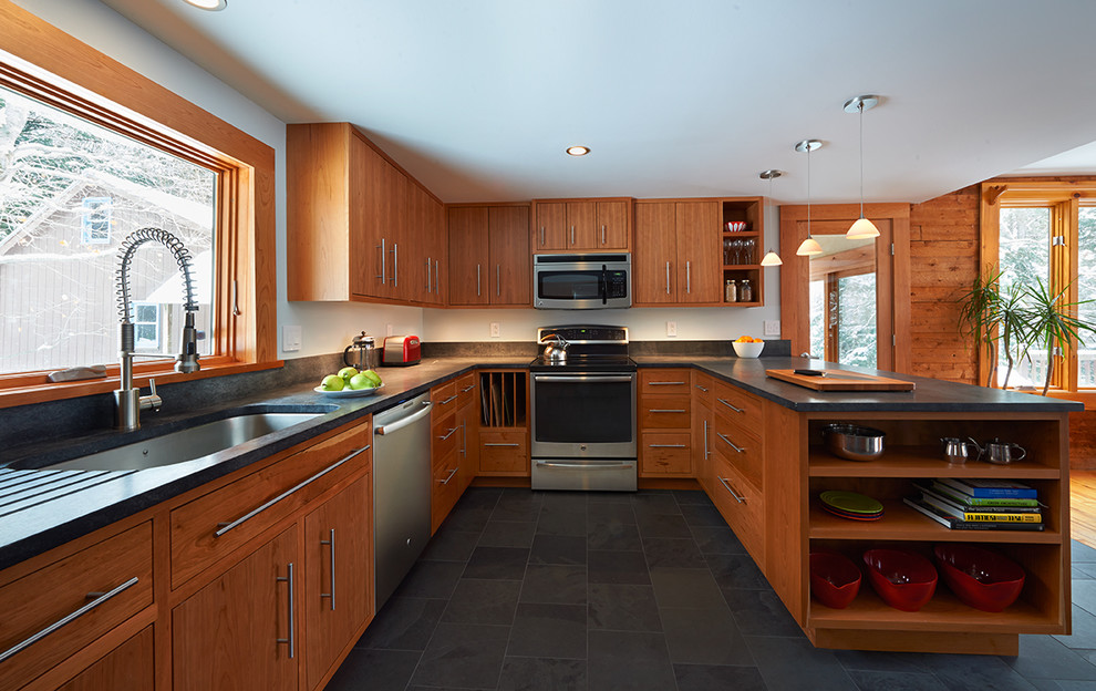 Eat-in kitchen - mid-sized contemporary u-shaped slate floor eat-in kitchen idea in Burlington with an undermount sink, flat-panel cabinets, medium tone wood cabinets, soapstone countertops, black backsplash, stainless steel appliances and a peninsula