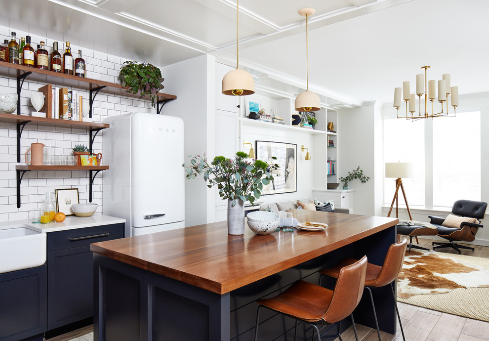 Modern inredning av ett litet kök, med en rustik diskho, skåp i shakerstil, blå skåp, träbänkskiva, vitt stänkskydd, stänkskydd i keramik, vita vitvaror, klinkergolv i porslin, en köksö och brunt golv