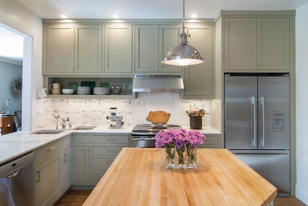 Diseño de cocina tradicional pequeña con fregadero bajoencimera, armarios estilo shaker, puertas de armario grises, encimera de mármol, salpicadero blanco, salpicadero de azulejos de piedra, electrodomésticos de acero inoxidable, suelo de madera clara y una isla