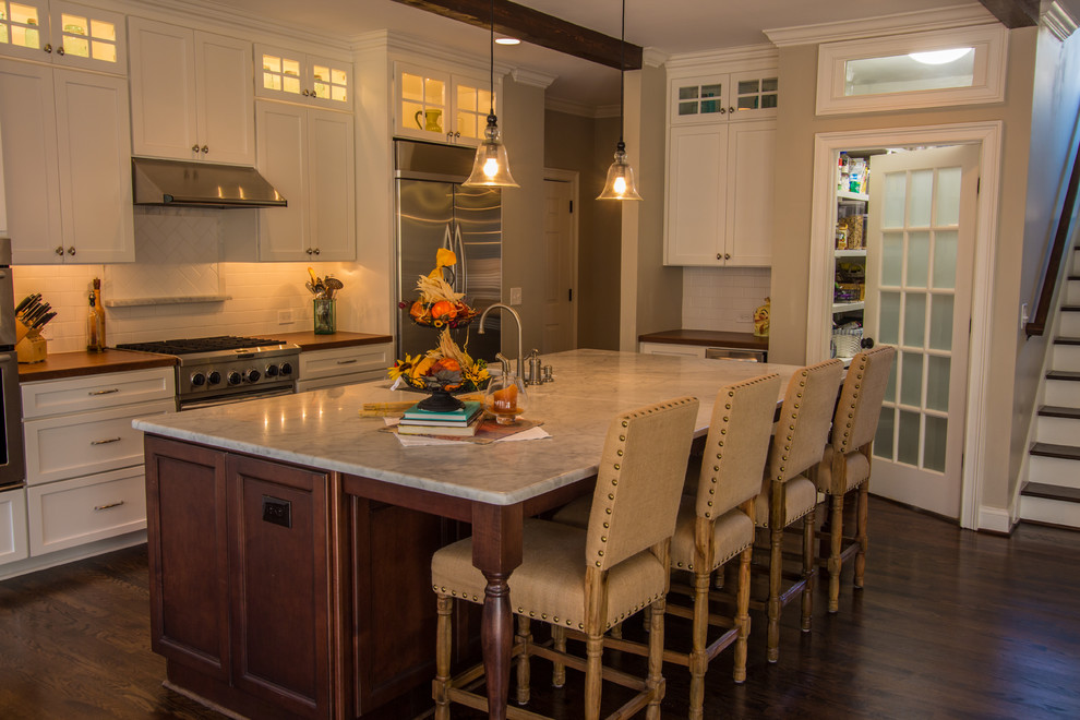 Example of a mid-sized classic single-wall dark wood floor eat-in kitchen design in Atlanta with an undermount sink, shaker cabinets, white cabinets, white backsplash, ceramic backsplash, stainless steel appliances, an island and marble countertops