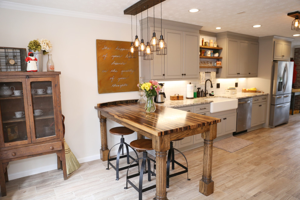 Foto på ett stort lantligt kök, med en rustik diskho, luckor med upphöjd panel, grå skåp, vitt stänkskydd, rostfria vitvaror, ljust trägolv, en halv köksö och brunt golv