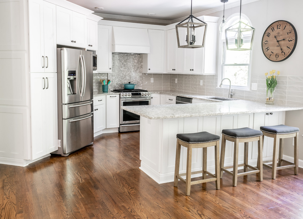 Inspiration for a mid-sized country u-shaped medium tone wood floor and brown floor enclosed kitchen remodel in Atlanta with an undermount sink, shaker cabinets, white cabinets, beige backsplash, ceramic backsplash, stainless steel appliances, a peninsula, gray countertops and quartz countertops