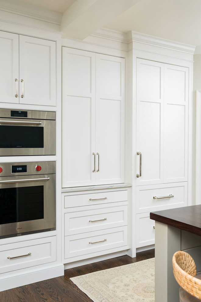 Foto på ett mellanstort vintage vit kök, med en rustik diskho, luckor med profilerade fronter, vita skåp, bänkskiva i kvartsit, grått stänkskydd, stänkskydd i keramik, integrerade vitvaror, mellanmörkt trägolv, en köksö och brunt golv