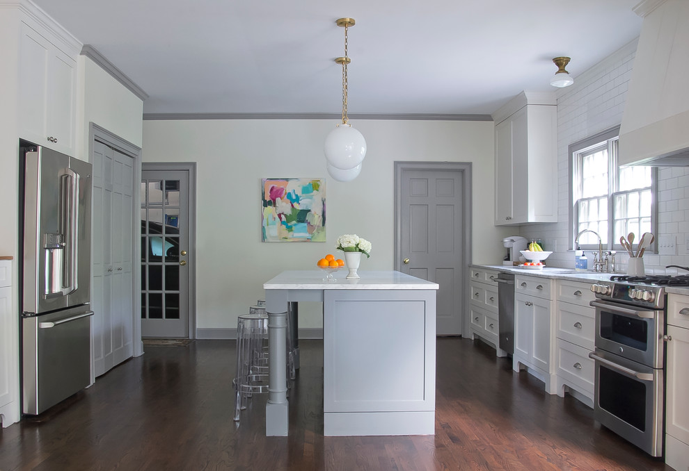 Zweizeilige Klassische Küche mit Unterbauwaschbecken, Schrankfronten im Shaker-Stil, weißen Schränken, Küchenrückwand in Weiß, Küchengeräten aus Edelstahl, dunklem Holzboden und Kücheninsel in Atlanta