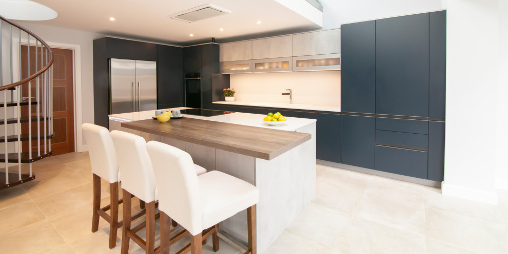 Inspiration for a medium sized contemporary l-shaped open plan kitchen in Berkshire with a built-in sink, flat-panel cabinets, blue cabinets, quartz worktops, black appliances, an island and white worktops.