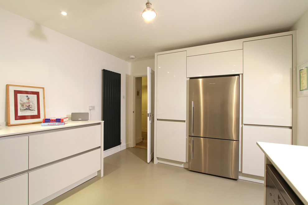 Example of a mid-sized minimalist u-shaped linoleum floor eat-in kitchen design in Hampshire with a single-bowl sink, flat-panel cabinets, white cabinets, quartz countertops, beige backsplash, glass sheet backsplash, colored appliances and a peninsula