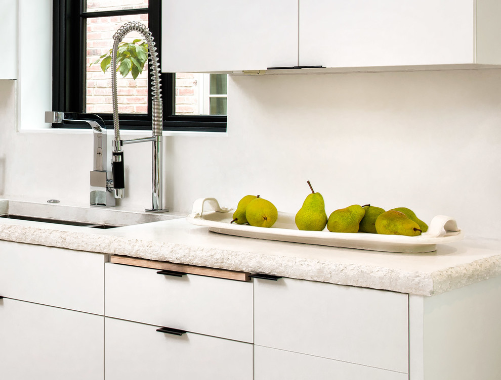 Foto di una cucina minimalista con lavello sottopiano, ante lisce, ante bianche, paraspruzzi con lastra di vetro, elettrodomestici in acciaio inossidabile e nessuna isola