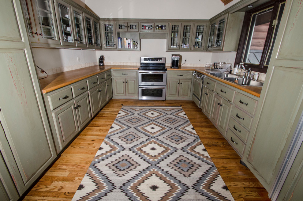 Rustik inredning av ett mellanstort kök, med en dubbel diskho, luckor med upphöjd panel, gröna skåp, träbänkskiva, beige stänkskydd, stänkskydd i keramik, rostfria vitvaror och mellanmörkt trägolv