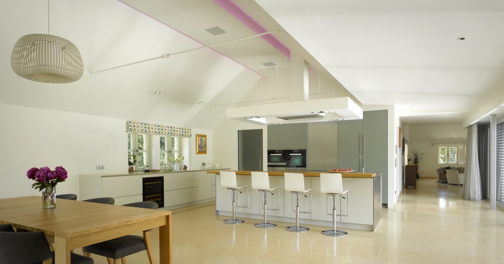 This is an example of a large contemporary kitchen in London with a submerged sink, flat-panel cabinets, grey cabinets, composite countertops, stainless steel appliances and an island.