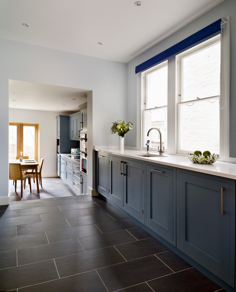 Offene, Große Moderne Küche mit Unterbauwaschbecken, flächenbündigen Schrankfronten, blauen Schränken und Mineralwerkstoff-Arbeitsplatte in London