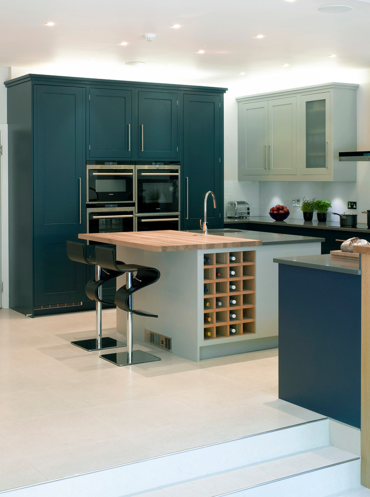 Large contemporary open plan kitchen in London with recessed-panel cabinets, blue cabinets and an island.
