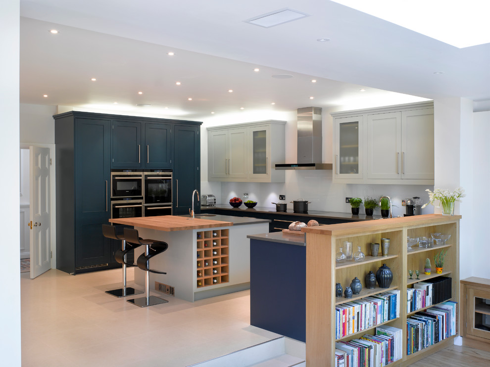 This is an example of a large contemporary open plan kitchen in London with recessed-panel cabinets, blue cabinets and an island.