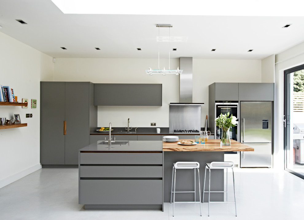Photo of a large contemporary open plan kitchen in London with a submerged sink, flat-panel cabinets, grey cabinets, composite countertops, stainless steel appliances and an island.