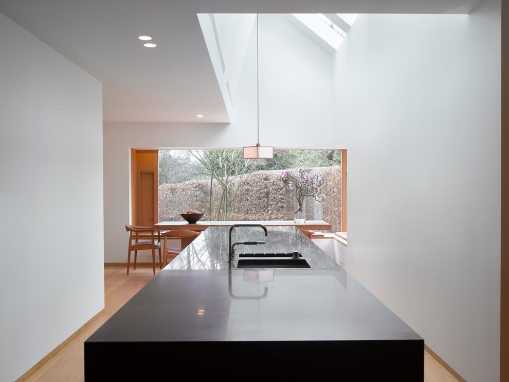 Immagine di una grande cucina minimal con lavello sottopiano, ante lisce, ante in legno scuro, top in superficie solida e pavimento in legno massello medio