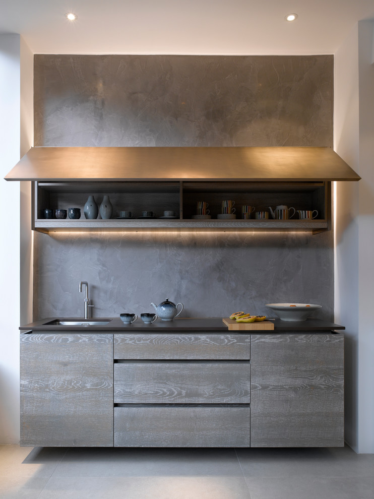 Inspiration pour une grande cuisine design avec un placard à porte plane, des portes de placard grises et un plan de travail en surface solide.