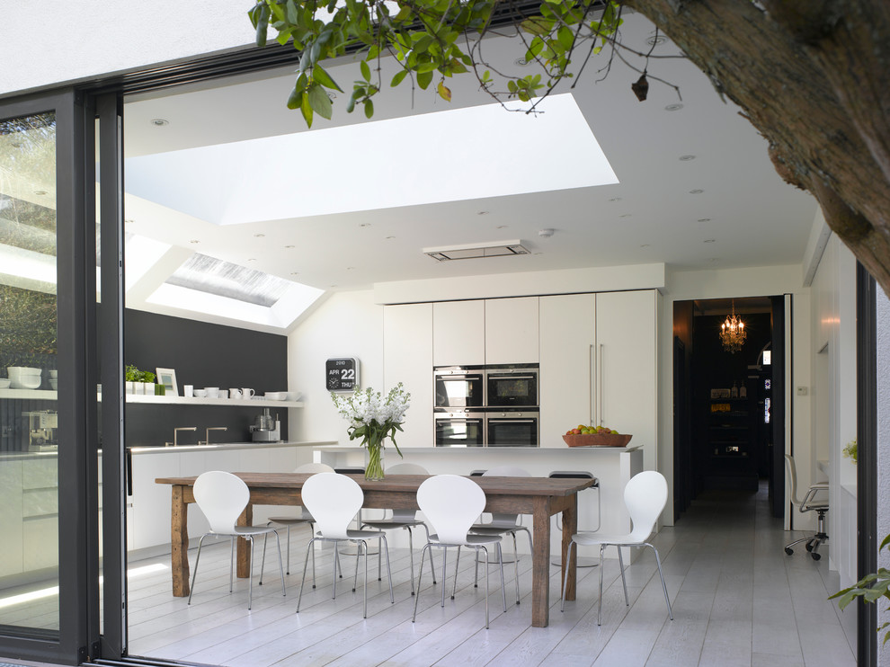 Inspiration for a large contemporary open plan kitchen in London with flat-panel cabinets and an island.