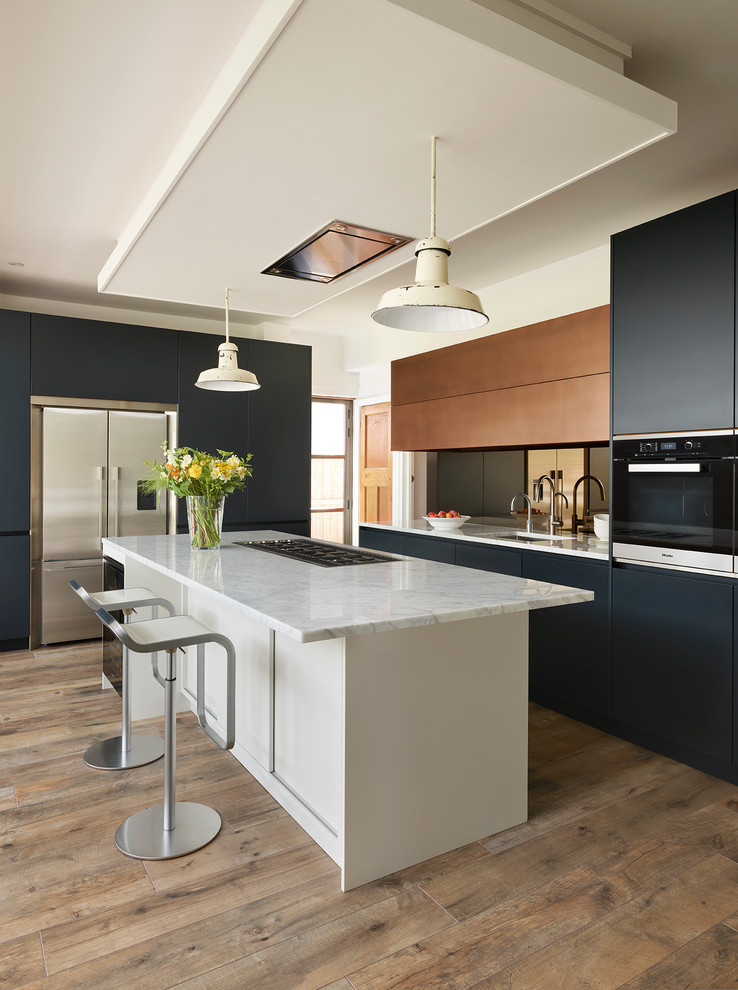 This is an example of a medium sized contemporary kitchen in London with flat-panel cabinets, blue cabinets, marble worktops, light hardwood flooring, a breakfast bar and brown floors.