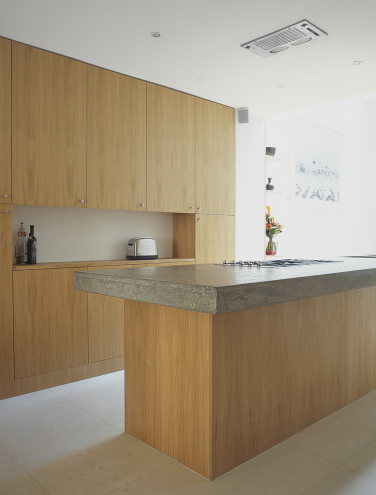 This is an example of a large contemporary open plan kitchen in London with a submerged sink, flat-panel cabinets, light wood cabinets, concrete worktops and an island.