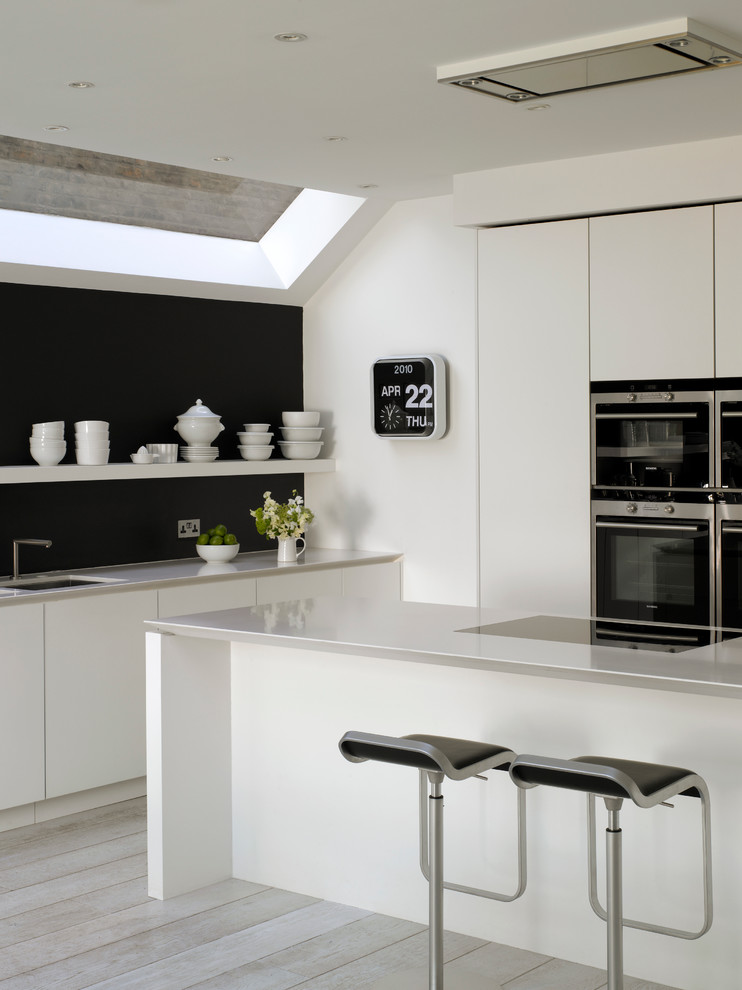 Photo of a large scandinavian open plan kitchen in London with a submerged sink, flat-panel cabinets, white cabinets, composite countertops and an island.