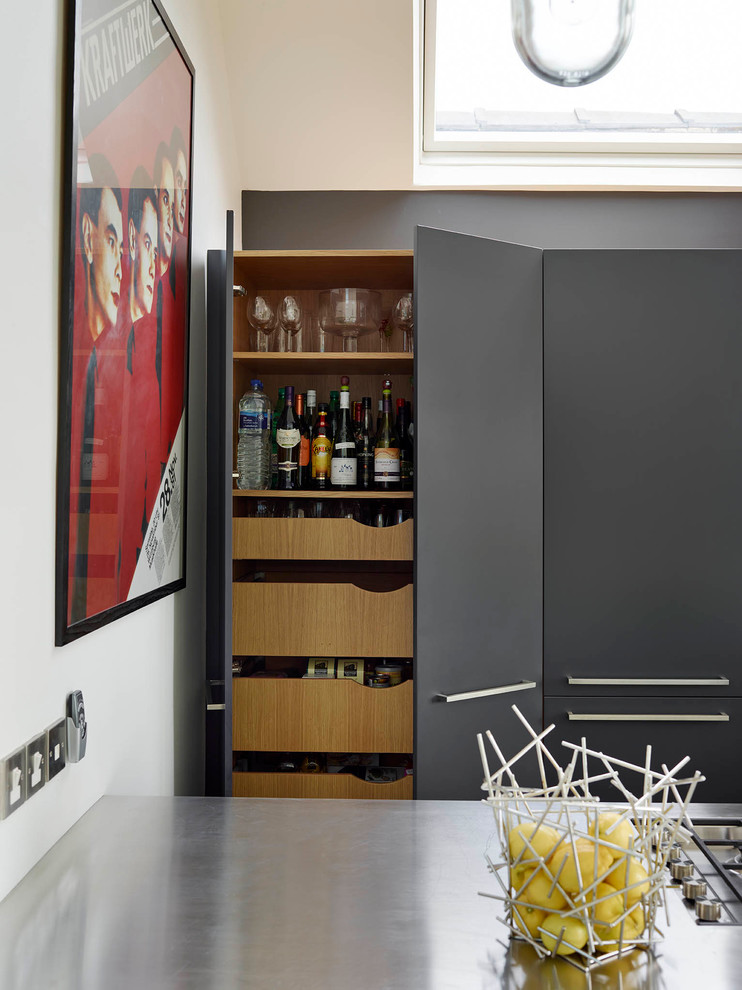 Photo of a large contemporary open plan kitchen in London with a submerged sink, flat-panel cabinets, grey cabinets, stainless steel worktops, white splashback, ceramic splashback, stainless steel appliances and an island.