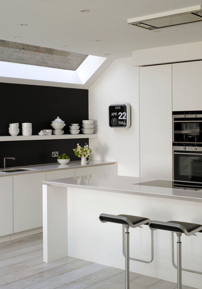 Example of a large trendy kitchen design in London with flat-panel cabinets, white cabinets, quartz countertops and an undermount sink