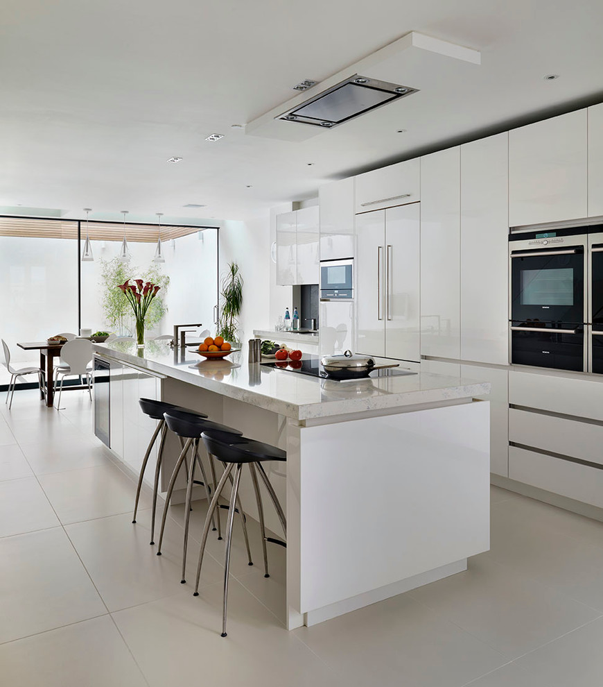 Inspiration for a large contemporary open concept kitchen remodel in London with an island, flat-panel cabinets, white cabinets, quartz countertops, stainless steel appliances and an undermount sink