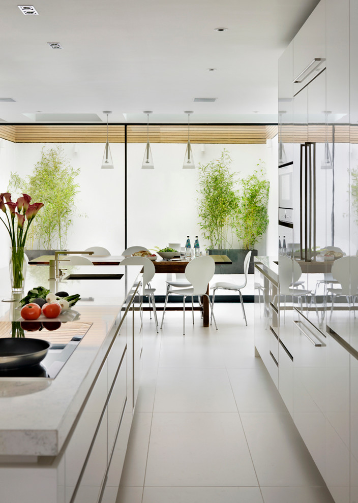 Große, Offene Moderne Küche mit Kücheninsel, weißen Schränken, flächenbündigen Schrankfronten, Quarzwerkstein-Arbeitsplatte, Küchengeräten aus Edelstahl und Unterbauwaschbecken in London