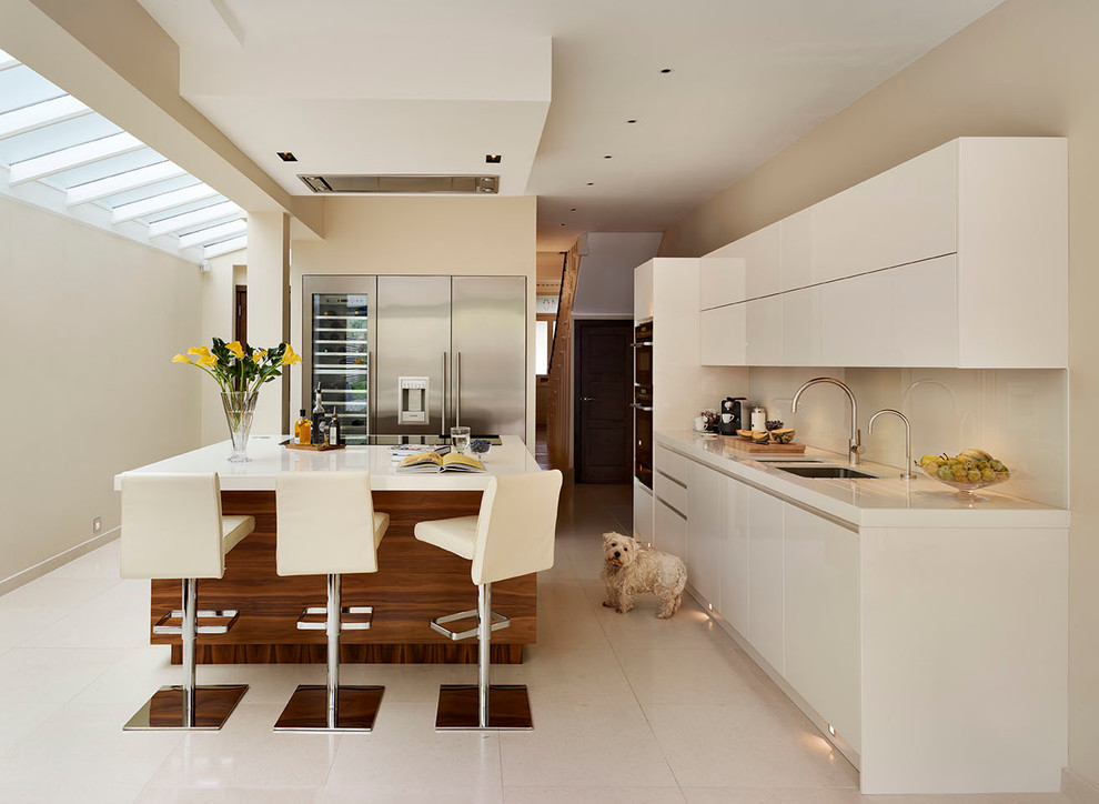 Große, Offene Moderne Küche mit Kücheninsel, weißen Schränken, Quarzwerkstein-Arbeitsplatte, Küchenrückwand in Weiß, Glasrückwand und Unterbauwaschbecken in London