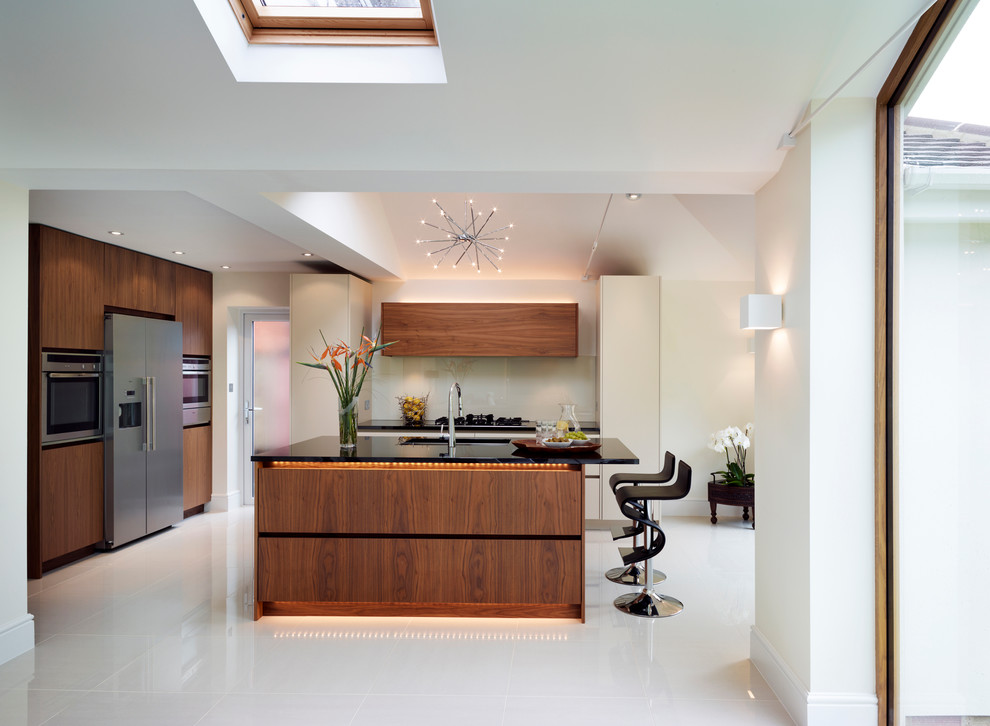 Photo of a large contemporary open plan kitchen in London with flat-panel cabinets, medium wood cabinets, granite worktops, an island, a submerged sink, beige splashback and stainless steel appliances.