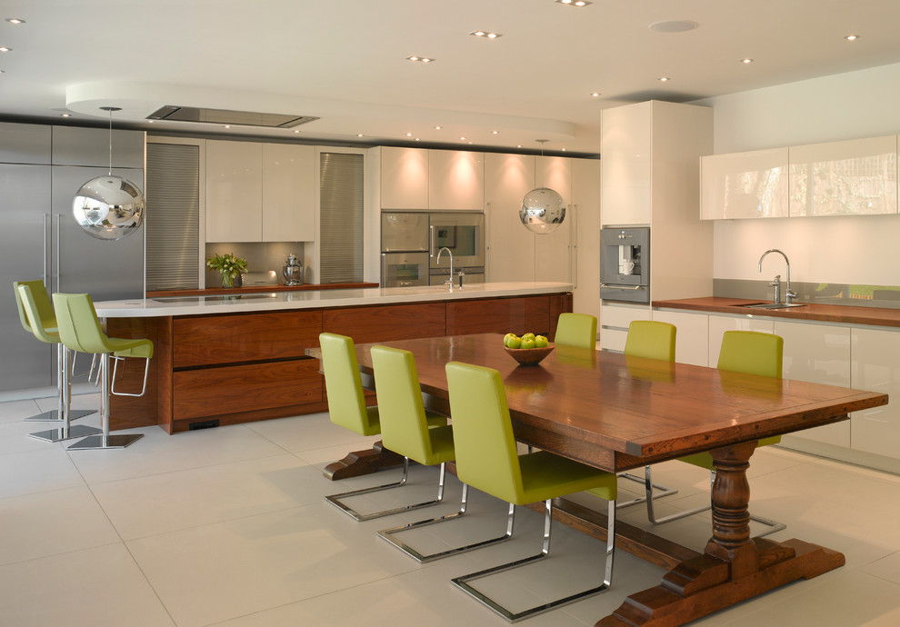 This is an example of a large contemporary open plan kitchen in London with flat-panel cabinets, white cabinets, wood worktops and an island.