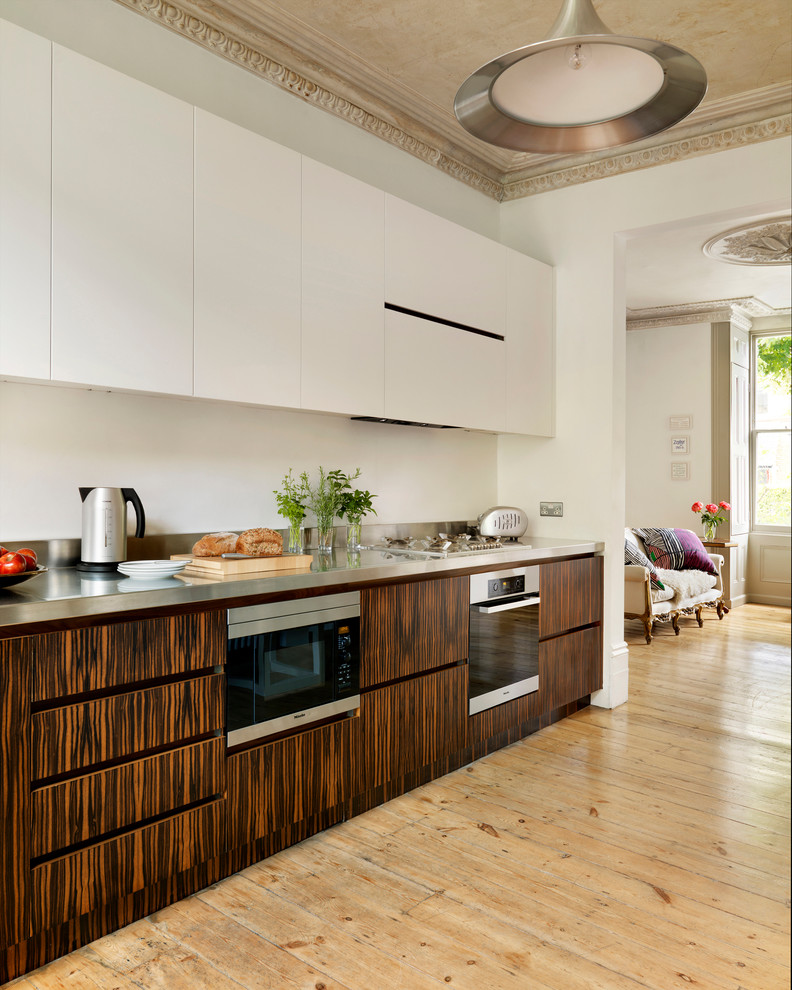 ロンドンにあるラグジュアリーな広いコンテンポラリースタイルのおしゃれなキッチン (フラットパネル扉のキャビネット、濃色木目調キャビネット、ステンレスカウンター、淡色無垢フローリング) の写真