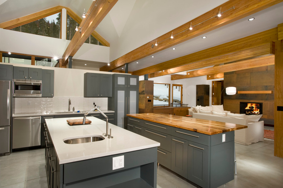 Ejemplo de cocina contemporánea con electrodomésticos de acero inoxidable, encimera de madera, puertas de armario grises y salpicadero blanco
