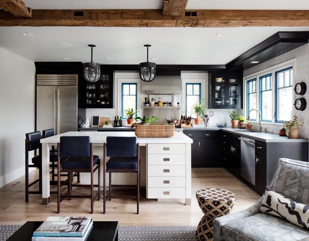 Bild på ett mellanstort eklektiskt kök, med en undermonterad diskho, svarta skåp, bänkskiva i kvarts, vitt stänkskydd, stänkskydd i keramik, rostfria vitvaror, ljust trägolv, en köksö och brunt golv