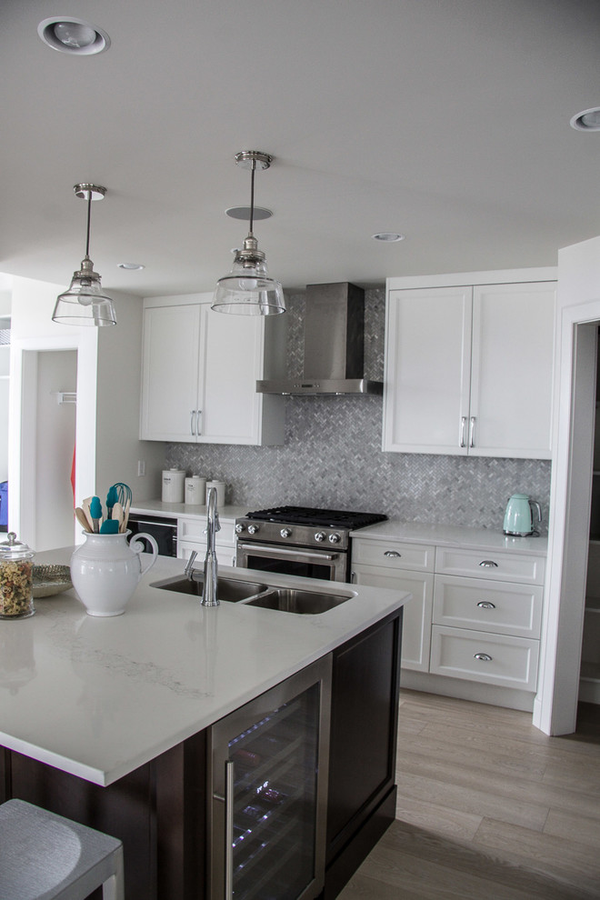 Mid-sized transitional l-shaped medium tone wood floor and gray floor open concept kitchen photo in Vancouver with gray backsplash, mosaic tile backsplash, a double-bowl sink, recessed-panel cabinets, white cabinets, solid surface countertops, stainless steel appliances and an island