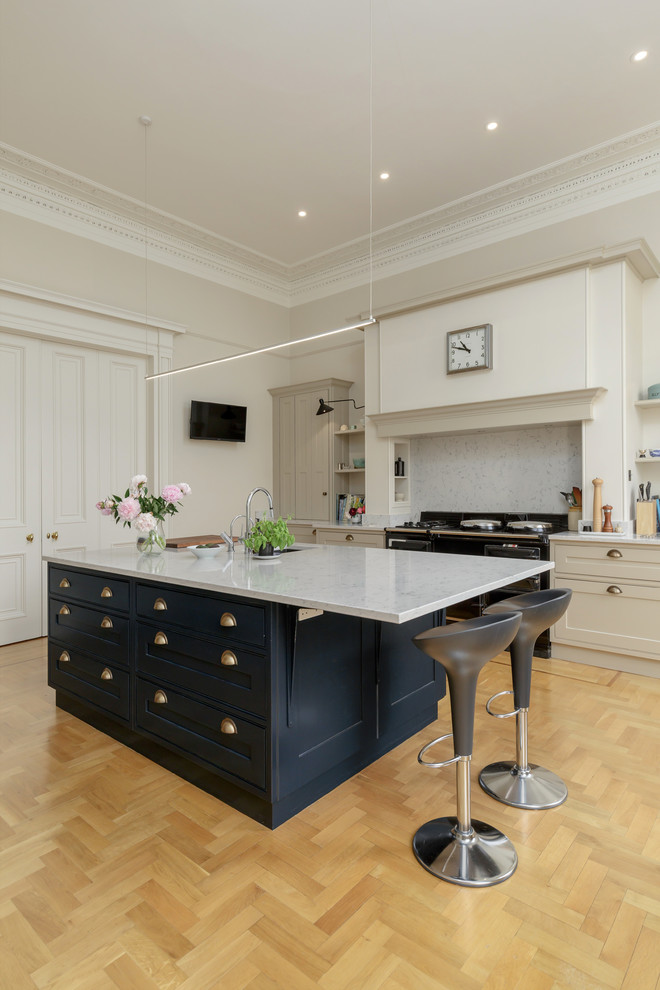 This is an example of a large contemporary galley kitchen/diner in Edinburgh with an integrated sink, shaker cabinets, blue cabinets, engineered stone countertops, integrated appliances, light hardwood flooring, an island, brown floors and grey worktops.