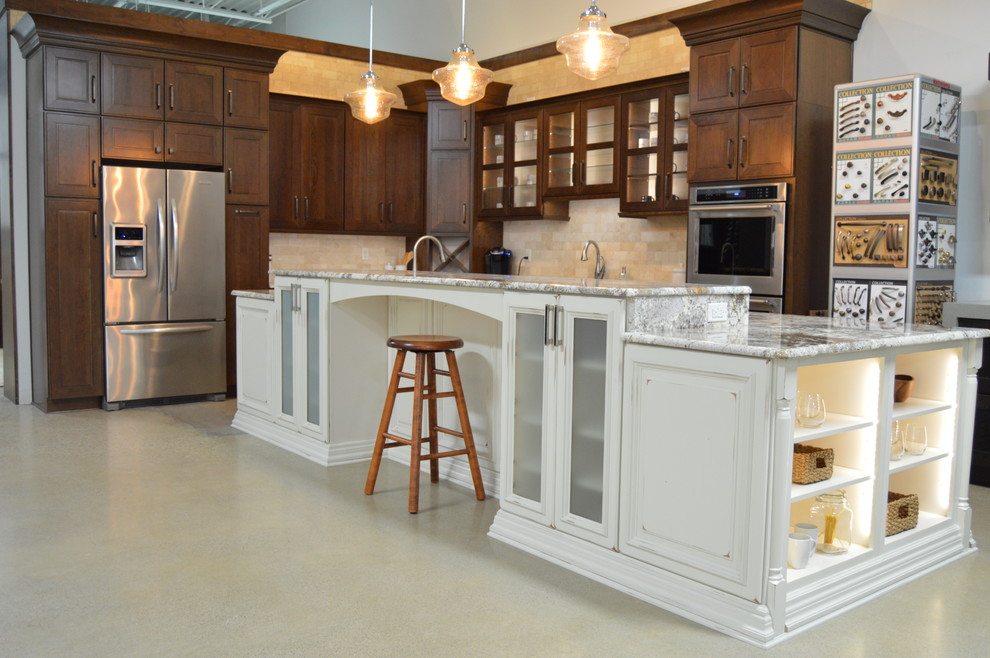 Cette photo montre une grande cuisine américaine chic en L et bois foncé avec un placard avec porte à panneau surélevé, une crédence beige, un électroménager en acier inoxydable et îlot.
