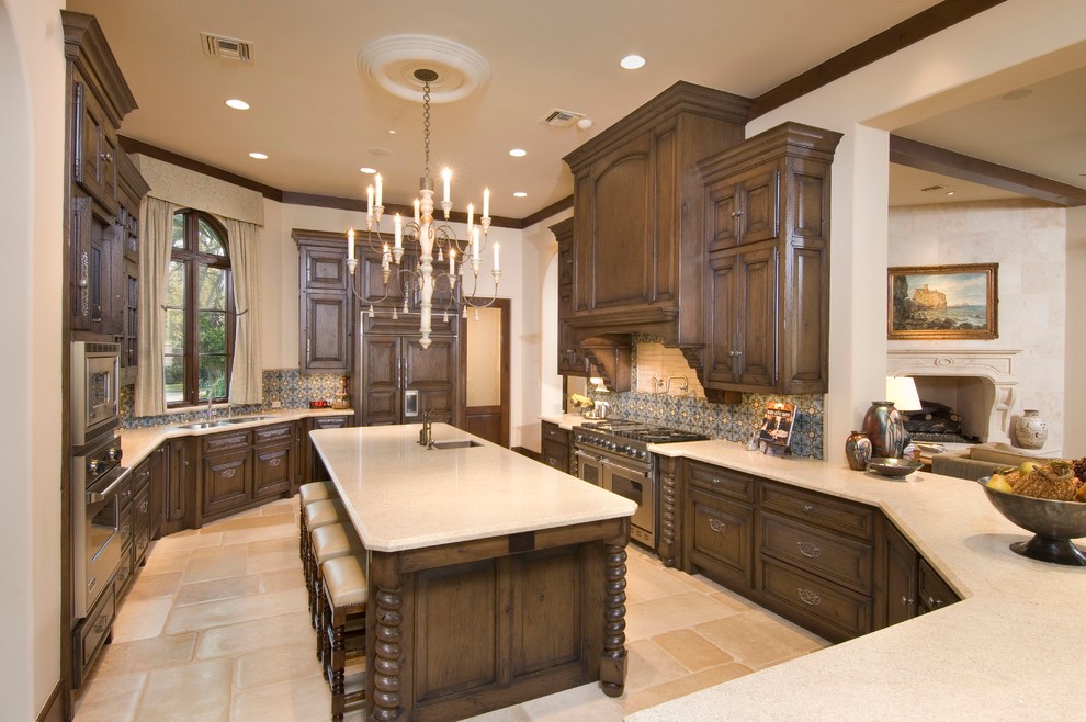 Example of a tuscan u-shaped travertine floor and beige floor open concept kitchen design in Houston with raised-panel cabinets, dark wood cabinets, granite countertops, cement tile backsplash, stainless steel appliances and two islands