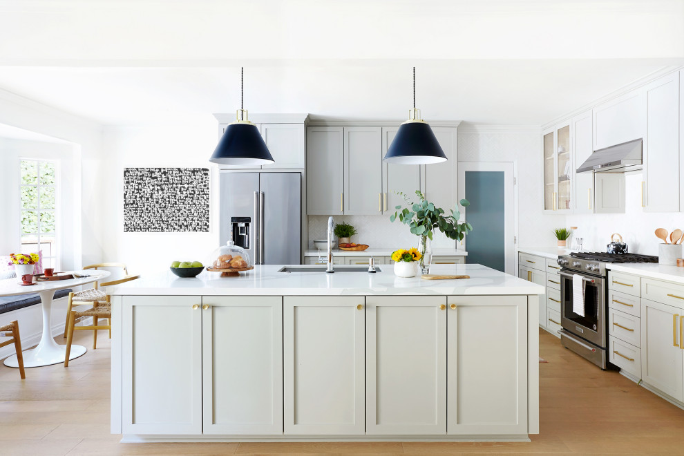 This is an example of a large contemporary u-shaped kitchen/diner in Los Angeles with a submerged sink, shaker cabinets, green cabinets, white splashback, mosaic tiled splashback, stainless steel appliances, medium hardwood flooring, an island, brown floors and white worktops.