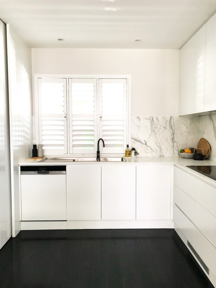 Example of a mid-sized minimalist u-shaped dark wood floor and black floor eat-in kitchen design in Sydney with an undermount sink, flat-panel cabinets, white cabinets, quartz countertops, multicolored backsplash, marble backsplash, stainless steel appliances and an island
