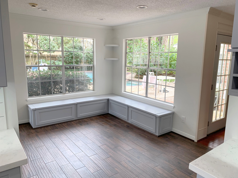 ヒューストンにある中くらいなトランジショナルスタイルのおしゃれなキッチン (シングルシンク、シェーカースタイル扉のキャビネット、グレーのキャビネット、珪岩カウンター、白いキッチンパネル、塗装板のキッチンパネル、シルバーの調理設備、ラミネートの床、茶色い床、白いキッチンカウンター) の写真