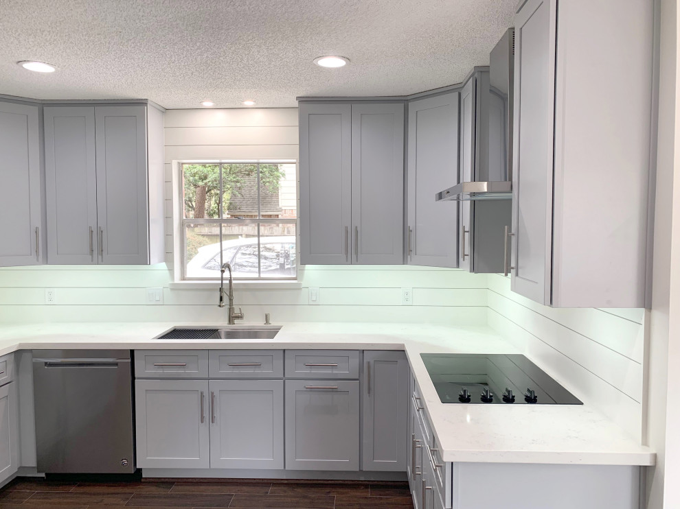 This is an example of a medium sized traditional kitchen in Houston with a single-bowl sink, shaker cabinets, grey cabinets, quartz worktops, white splashback, tonge and groove splashback, stainless steel appliances, laminate floors, brown floors and white worktops.