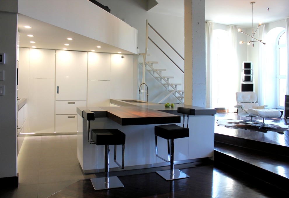 Immagine di una grande cucina minimalista con lavello sottopiano, elettrodomestici in acciaio inossidabile, parquet scuro, ante lisce, ante bianche e top in legno
