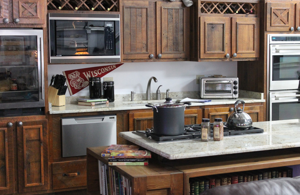 Esempio di una cucina rustica di medie dimensioni con lavello a doppia vasca, ante lisce, ante con finitura invecchiata, top in granito, paraspruzzi beige e elettrodomestici in acciaio inossidabile