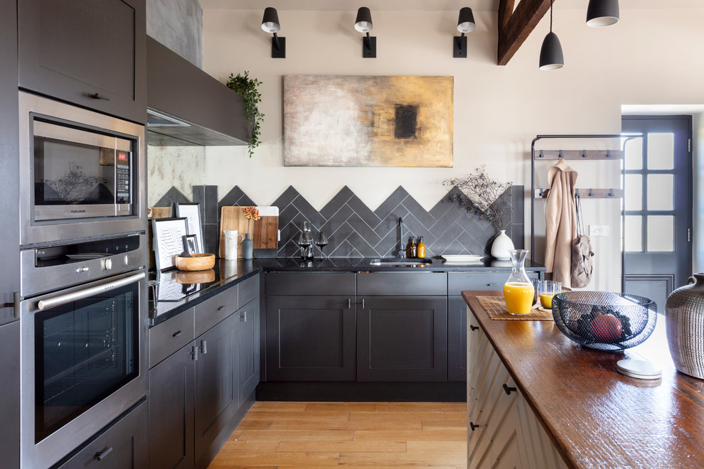 Exempel på ett mellanstort rustikt svart svart kök, med en enkel diskho, svarta skåp, bänkskiva i koppar, svart stänkskydd, integrerade vitvaror, ljust trägolv, en köksö och brunt golv