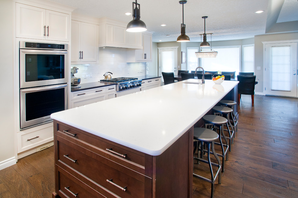 Inspiration for an u-shaped eat-in kitchen remodel in Calgary with an undermount sink, shaker cabinets, white cabinets, white backsplash, subway tile backsplash and stainless steel appliances