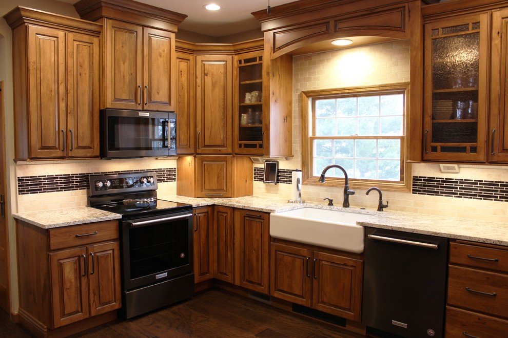 Foto på ett stort rustikt beige kök, med en rustik diskho, luckor med upphöjd panel, skåp i mellenmörkt trä, granitbänkskiva, beige stänkskydd, stänkskydd i travertin, svarta vitvaror, mellanmörkt trägolv, en halv köksö och brunt golv